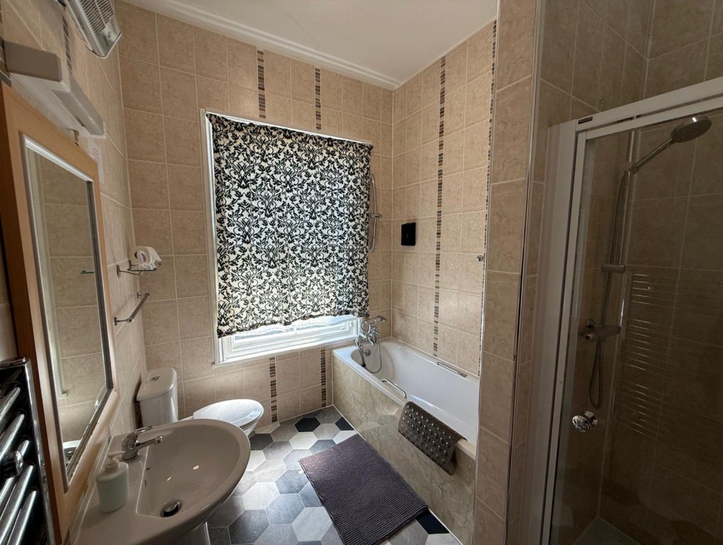 Modern ensuite bathroom with bathtub, glass shower, pedestal sink, and hexagonal floor tiles